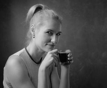 一位美丽的中年妇女带着一杯咖啡的肖像。 迷人而快乐的金发女郎喝咖啡。 复制空间。 黑白的。