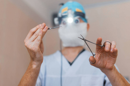 戴着眼镜戴着双眼百叶窗的外科医生站在手术室里拿着手术剪刀。操作流程