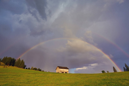 彩虹在田野树木和山脉中的乡村彩虹。