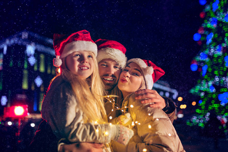 家庭圣诞节假期季节和人们的概念幸福的家庭灯光城市背景和夜间下雪