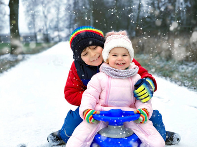 小孩男孩和可爱的幼儿女孩坐在一起的雪橇。兄弟姐妹, 兄弟和小妹妹享受雪橇骑在降雪期间。孩子们在雪地上雪橇。积极的乐趣为家庭度假