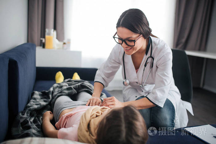 积极开朗的年轻女医生微笑她低下头摸着女孩的肚子医生检查它孩子直接