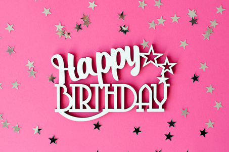 木制铭文生日快乐,粉红色背景与银星.照片