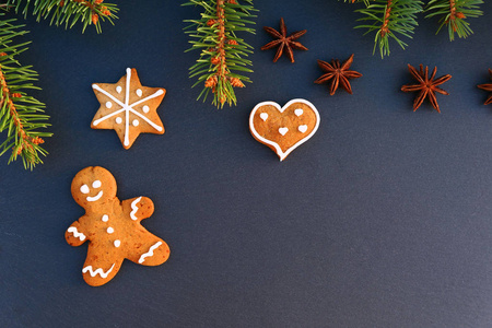 圣诞节边界由云杉树枝姜饼人饼干在黑暗的石板背景。