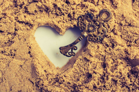 复古风格的钥匙和用棕色沙子做的心形