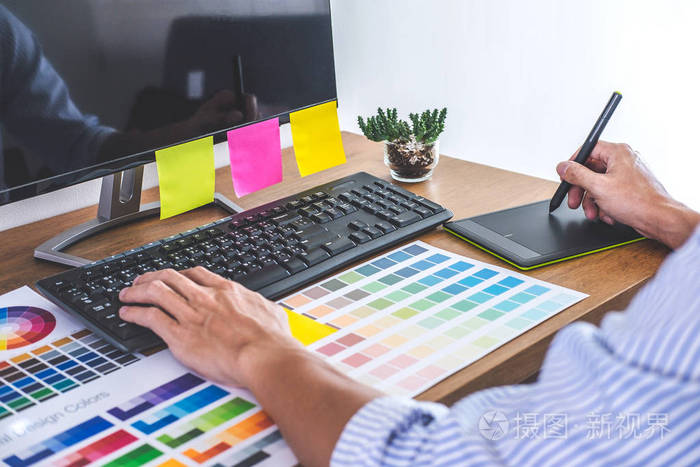 男性创意平面设计师在工作场所使用工作工具和附件进行颜色选择和绘制