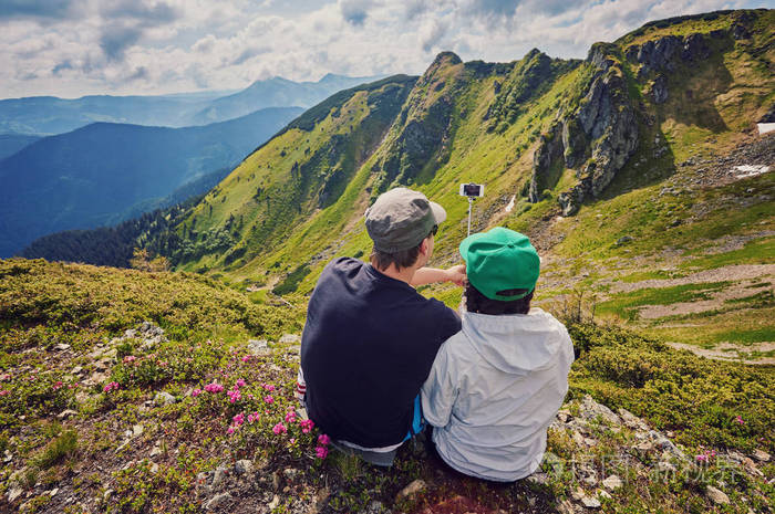 年轻夫妇徒步旅行用智能手机自拍幸福的青年男女以山景为背景拍摄自我