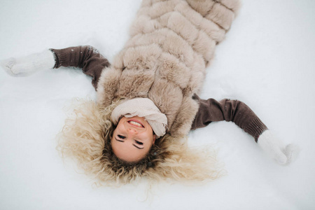 图为金发女郎躺在雪中散步