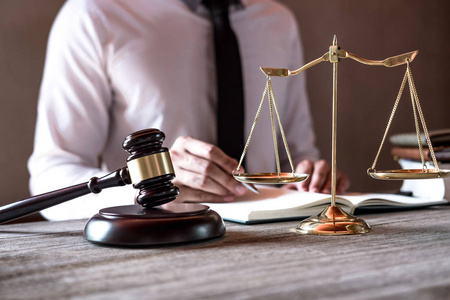 司法概念专业男性律师在法庭上坐在桌子旁,用木槌和司法天平签署文件