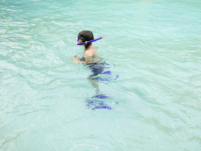 少年男孩，年轻的浮潜者，在美丽的蓝色水中游泳。 暑假和假期概念。