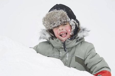 戴着帽子的男孩在雪堆里翻着耳朵