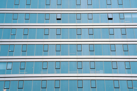 玻璃蓝色窗户的立面现代城市商务大厦摩天大楼。 新社区的现代公寓楼。 建筑物纹理的窗户。