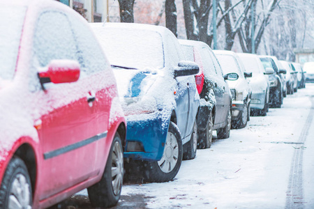 在寒冷的冬日，停在满是雪的街道上的汽车