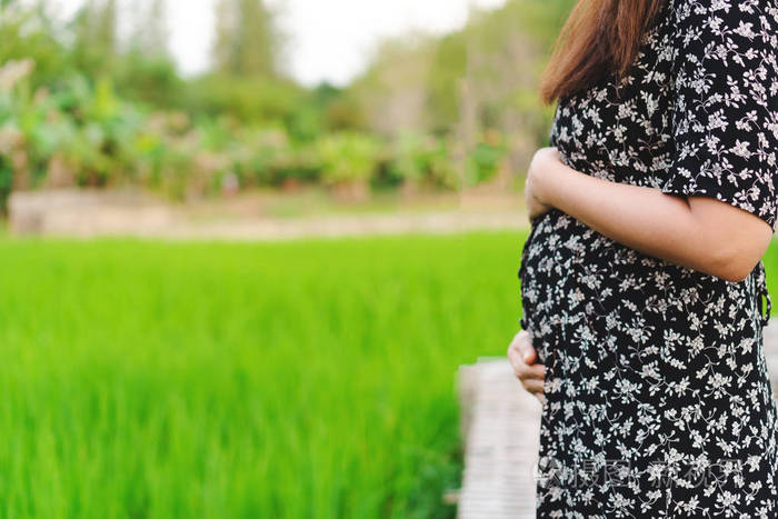 怀孕女孩在公园外放松,清新的空气和自然背景.