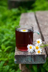 花园里木制的旧背景上的一束洋甘菊花和草药茶。 乡村静物