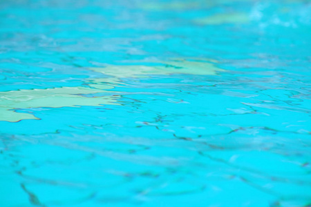 游泳池里有纯蓝色的水。 水背景。 游泳池底部的病因波纹和流动与波浪背景。 游泳池里的水荡漾着水的细节背景。