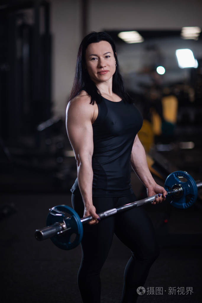 运动健身女孩在健身房训练二头肌和杠铃