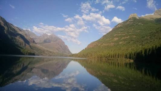 蒙大拿州金特拉湖冰川国家公园。 美丽的倒影在湖边，两旁是树木和山峰的森林。 乌托邦天堂远离城市和人群，非常和平。 令人敬畏的背景