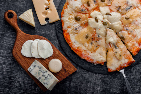 意大利披萨，石头上有不同种类的奶酪和一块黑色的粉笔板。 意大利传统食品。 上面的风景。