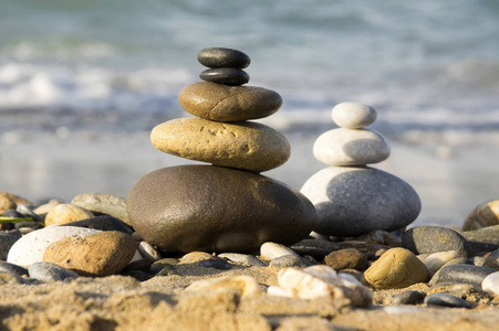 和谐和平衡的石头靠海岩禅宗雕塑阳光明媚的一天，两塔光明和黑暗的沙滩