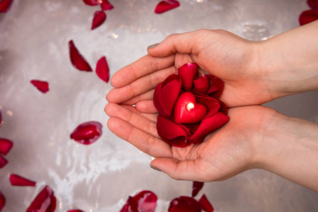 亲密的女人手里拿着红色的玫瑰花瓣,自理家庭,情人节惊喜照片