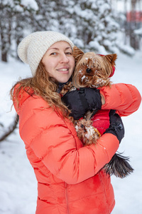 快乐的女人抱着约克郡猎犬在户外的冬季公园