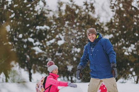 年轻的家庭妇女和男人穿着温暖的衣服，在雪地公园或户外森林里堆雪人。 假日的冬季乐趣休闲。 家庭生活方式观念