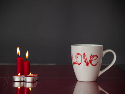 爱的概念，平静的生活，用红色的蜡烛和一个早餐杯，用爱这个词