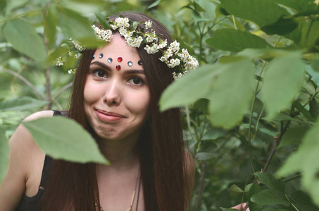 s head is wearing a floral wreath, on her forehead shiny decorat