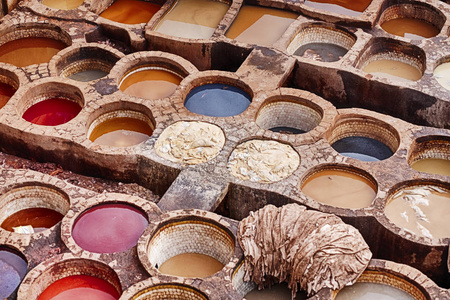 露天历史上的Chouara皮革制革厂在FES摩洛哥充满了石缸，其中含有染料和动物皮正在着色。