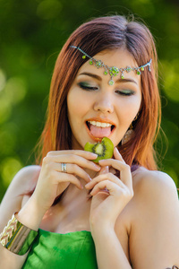 一位穿着绿色衣服头上戴戴德玛拿着猕猴桃片的美丽年轻亚洲女子的肖像