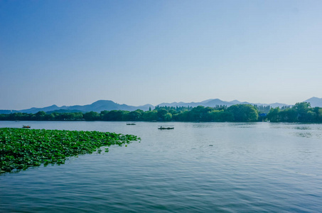 杭州西湖及周边丘陵的平静水景，船在水上航行