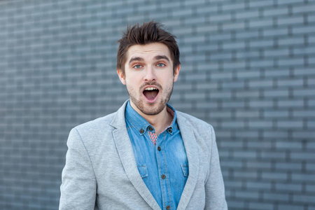 这是一幅令人惊讶的英俊的胡子男人的画像,他站在那里,张嘴看着镜头