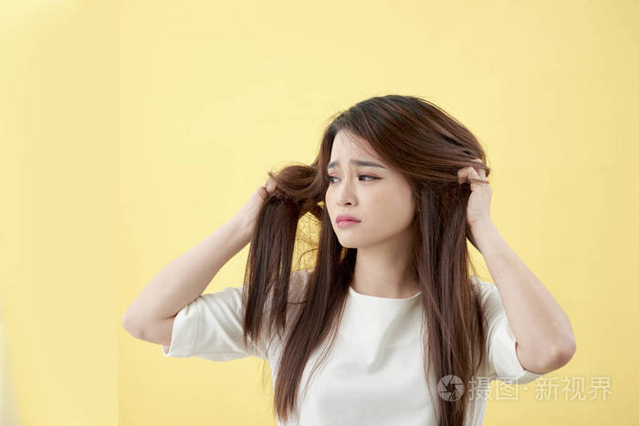 美丽迷人的年轻亚洲女人看着受损的干头发感觉如此悲伤和忧虑孤立在