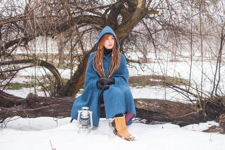 穿着复古蓝色外套的年轻女人在冬天的雾中公园散步，雪和树背景，幻想或仙女的概念