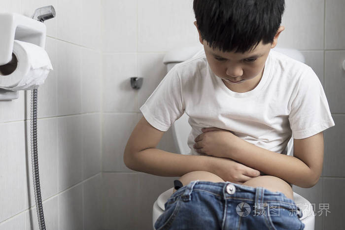 亚洲男孩坐在马桶上健康问题的概念
