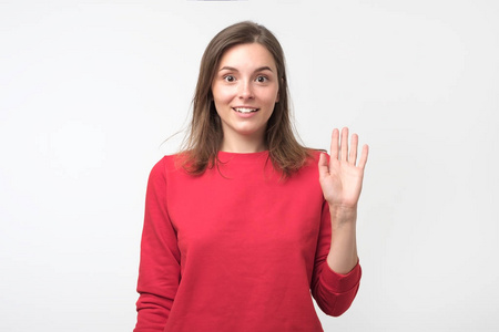 打招呼表情友好的欧洲少年穿着红色套头衫,挥手打招呼.