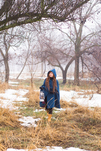 穿着复古蓝色外套的年轻女人在冬天的雾中公园散步，雪和树背景，幻想或仙女的概念