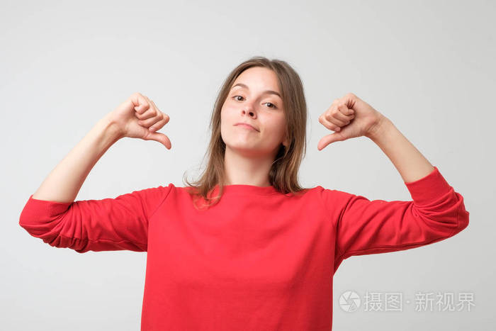 年轻漂亮的女人穿着红色毛衣,骄傲自信,手指着榜样.