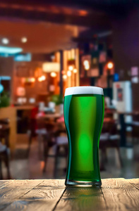 酒吧的木制酒吧柜台上一杯新鲜的绿色啤酒