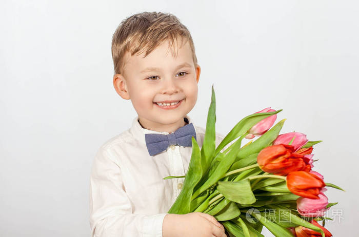 可爱的小男孩捧着一束花郁金香母亲节国际妇女节一个快乐的小男孩的
