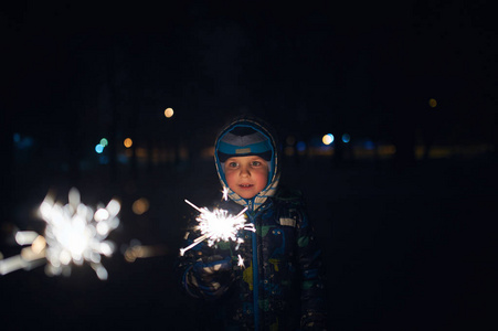 晚上在街上庆祝新年时, 男孩手里拿着一个火花