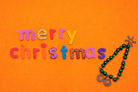 一棵珠子圣诞树和橙色背景下的圣诞快乐