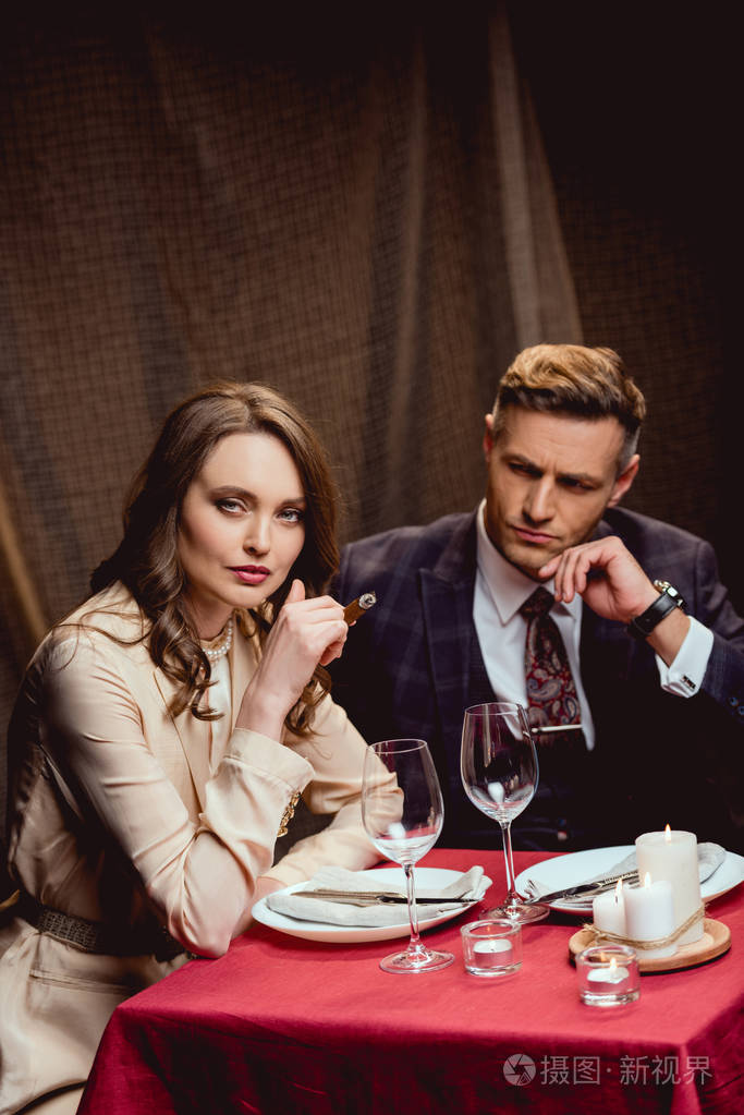 坐在餐桌边抽雪茄的美女与帅哥在餐厅浪漫晚餐