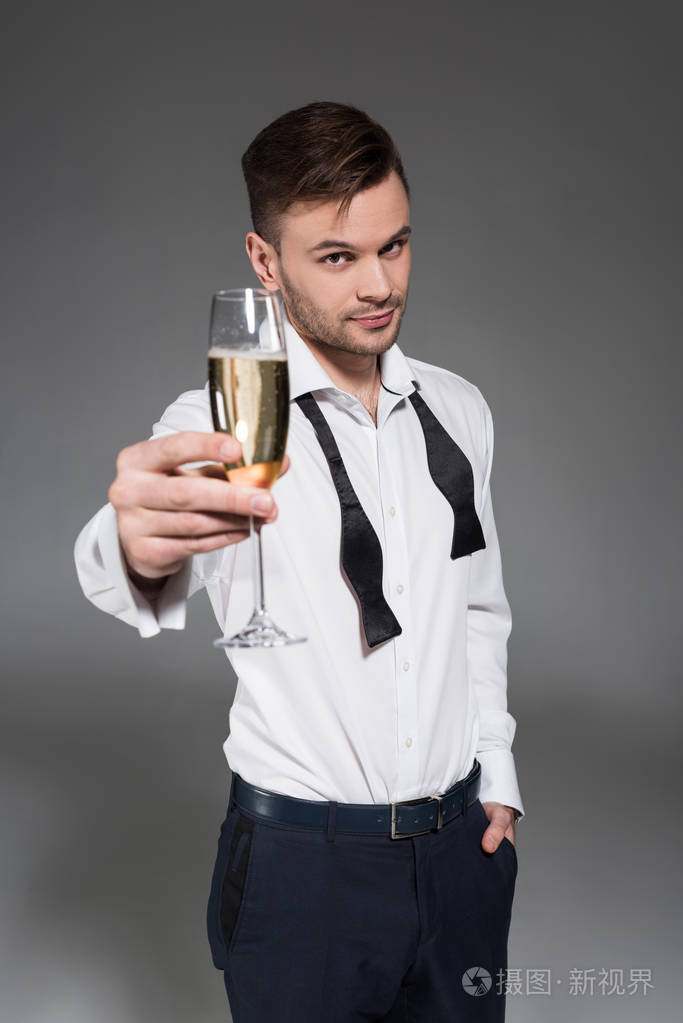 一个英俊的男人,用一杯隔离在灰色上的香槟品酒