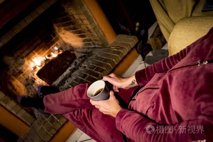 女人正在壁炉里取暖,而她正在喝咖啡