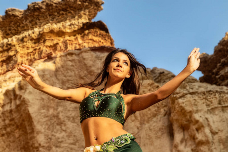 年轻的女孩穿着绿色的裙子，在纳米贝沙漠峡谷的神话空间里跳着著名的肚皮舞。 非洲。 安哥拉。
