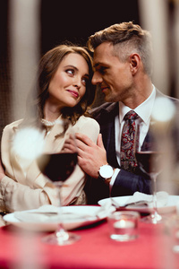 在餐厅的浪漫约会中，男人拥抱美丽的微笑的女人