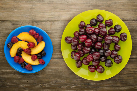 浆果樱桃在木制背景上的盘子上。 水果饮食。 素食食品。