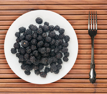 木背景上盘子上的黑莓。 素食。 健康的饮食。